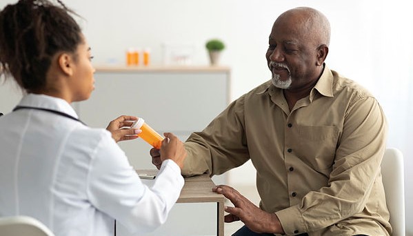 A doctor shows a bottle of pills to a patient