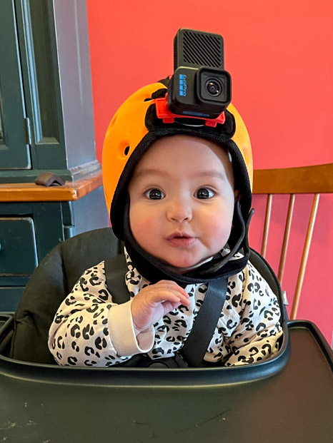 baby wearing a camera on head sitting in a high chair